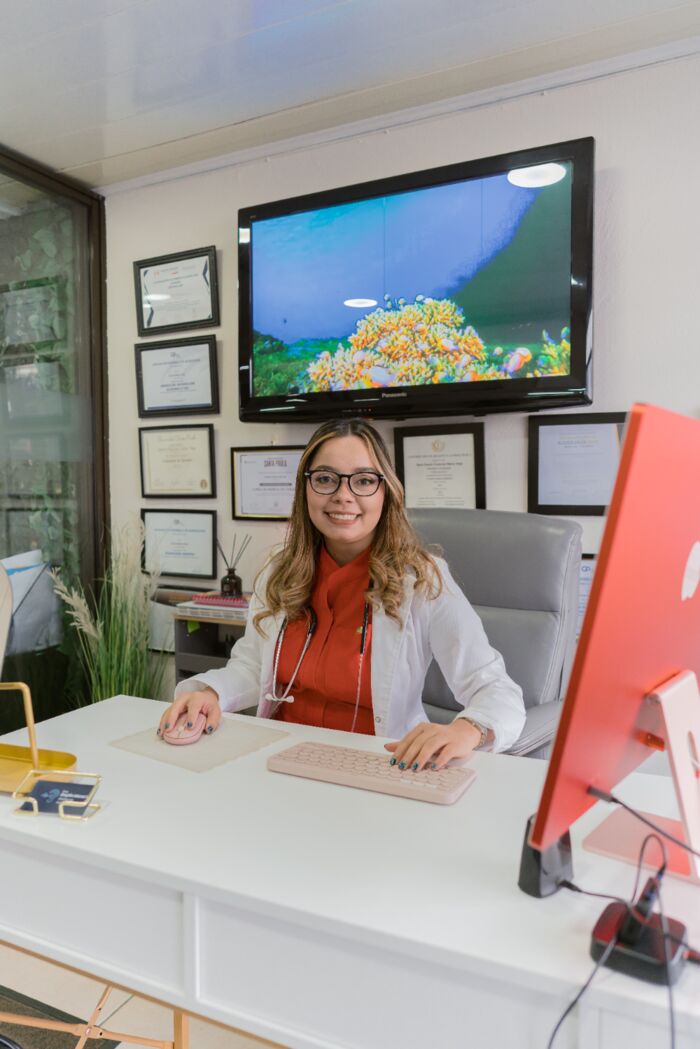 Deylin Mena Vega en su consultorio, junto a sus certificaciones